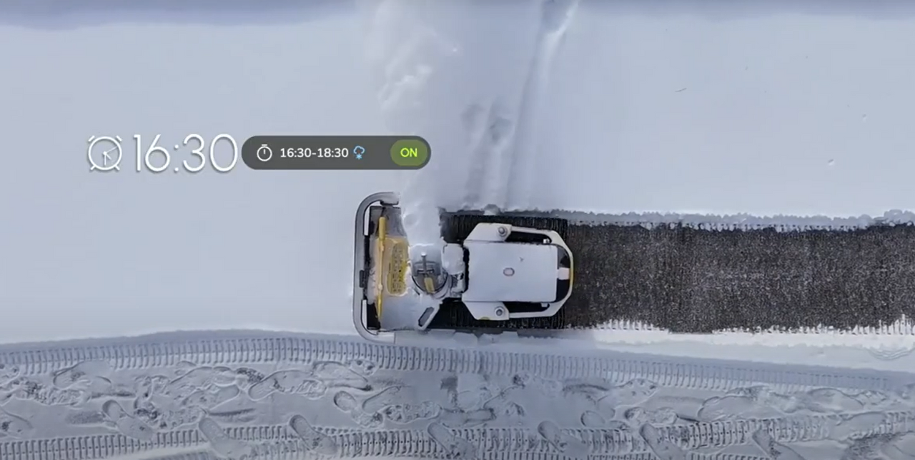 Robotic Yarbo snow blower clears path automatically, leaving clean driveway in snowy yard.