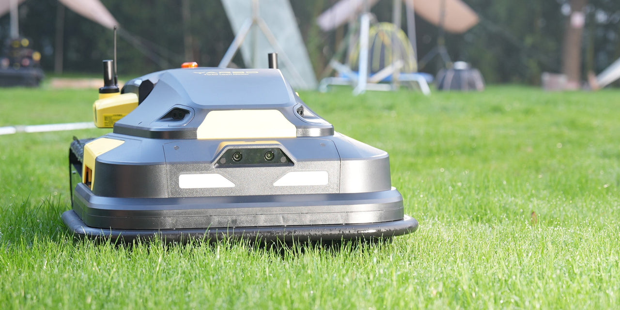 Robotic lawn mower on vibrant green grass, sleek gray and yellow design, modern tech for large property upkeep.