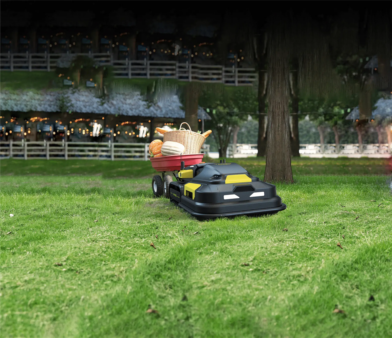 Black and yellow Yarbo robotic mower pulls red wagon with pumpkins and basket across lush green lawn.