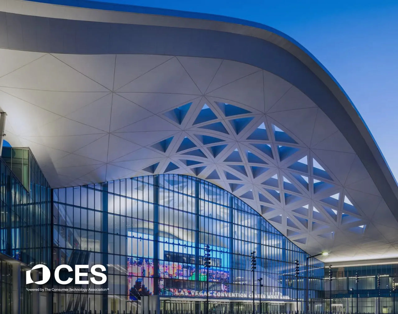 Modern white arched roof with geometric triangular patterns over glass facade at dusk, CES logo visible.