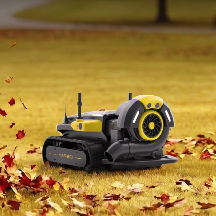 Yellow and black YARBO robotic lawn mower on grass with scattered red autumn leaves, front-facing with visible fan and tracks.