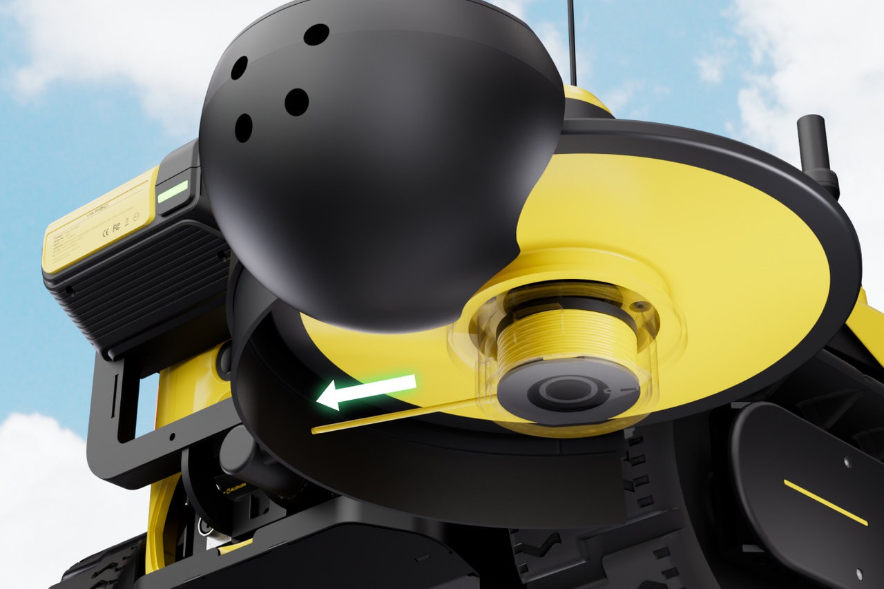 Close-up of yellow and black robotic lawn mower with spinning blade, green arrow indicating motion, against blue sky background.