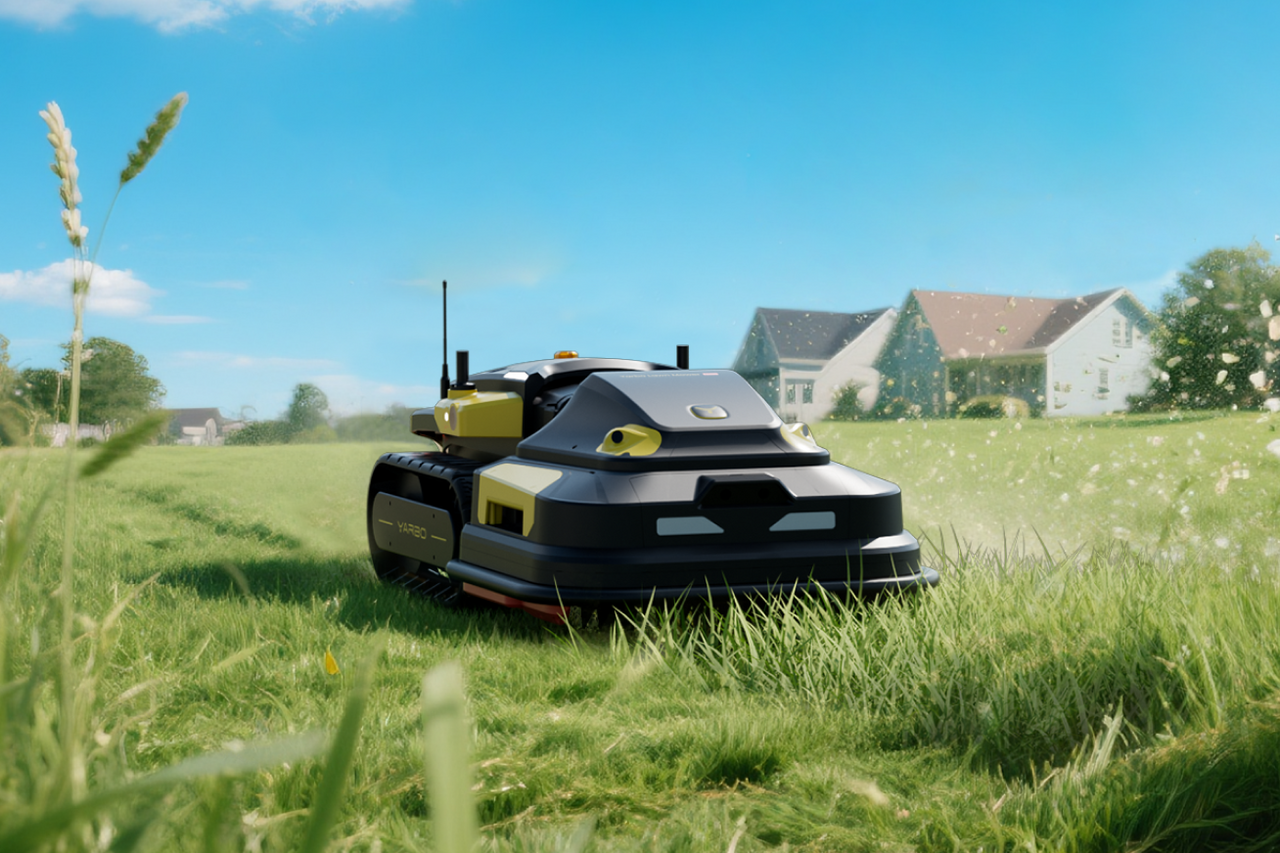 Black and yellow robotic lawn mower on green grass with houses and blue sky in background.