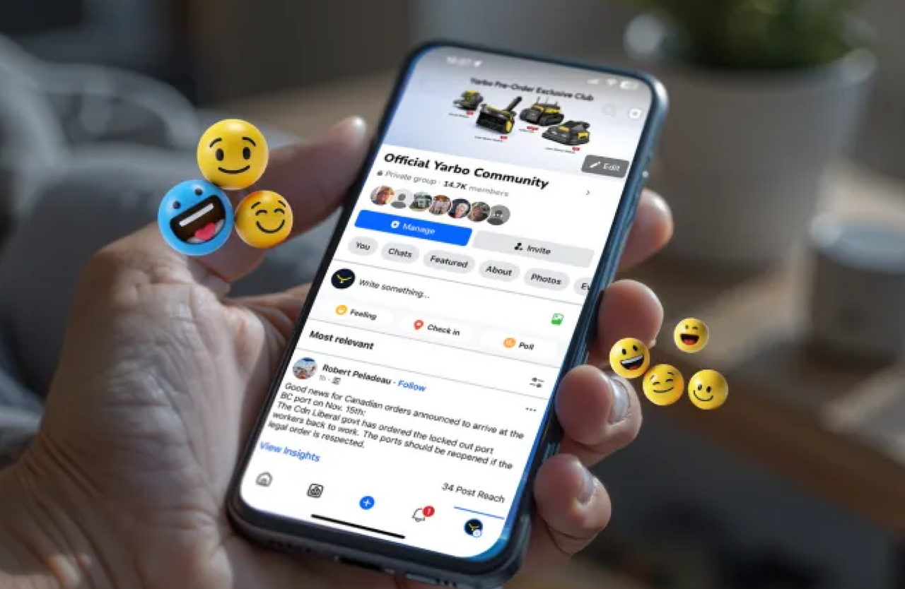 Hand holding smartphone displaying "Official Yarbo Community" Facebook group with emojis floating around, bright screen, casual indoor setting.