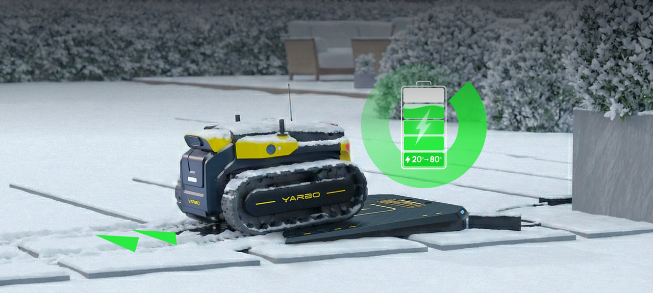 Yellow and black YARBO robot on snowy patio, charging on dock, green battery icon shows 20–80% charge range.