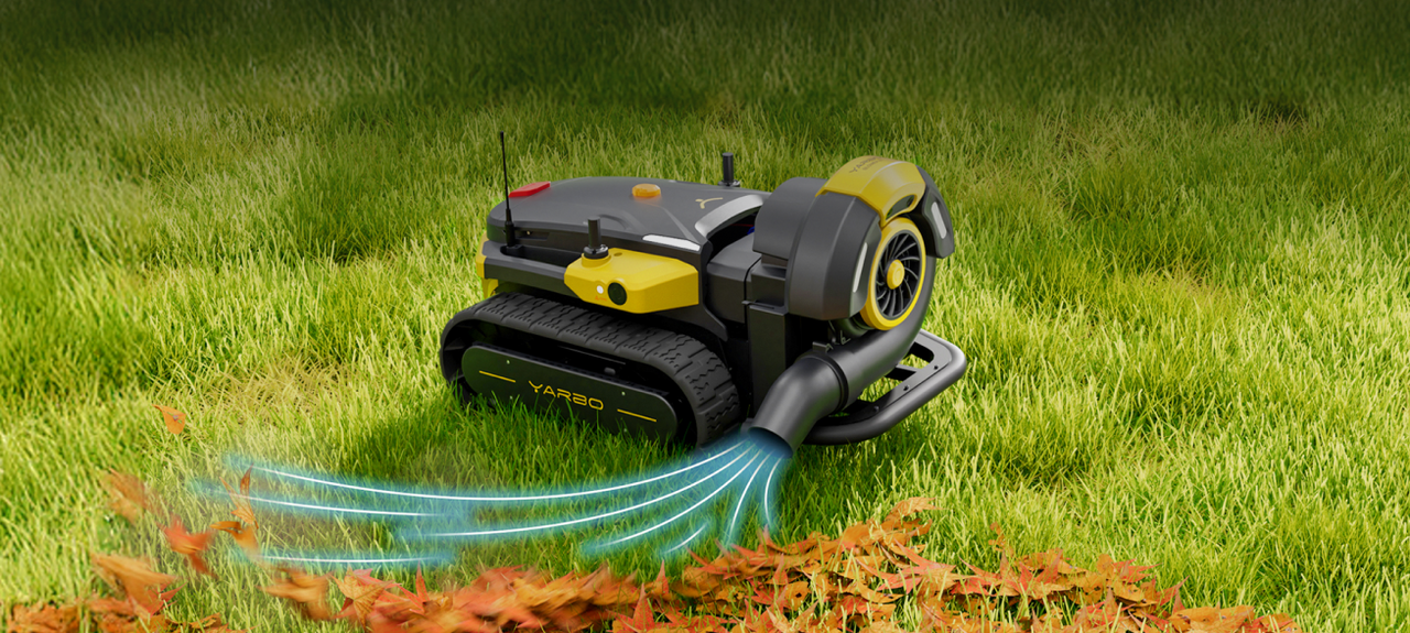 Yellow and black YARBO robotic lawn mower blowing orange leaves on green grass.
