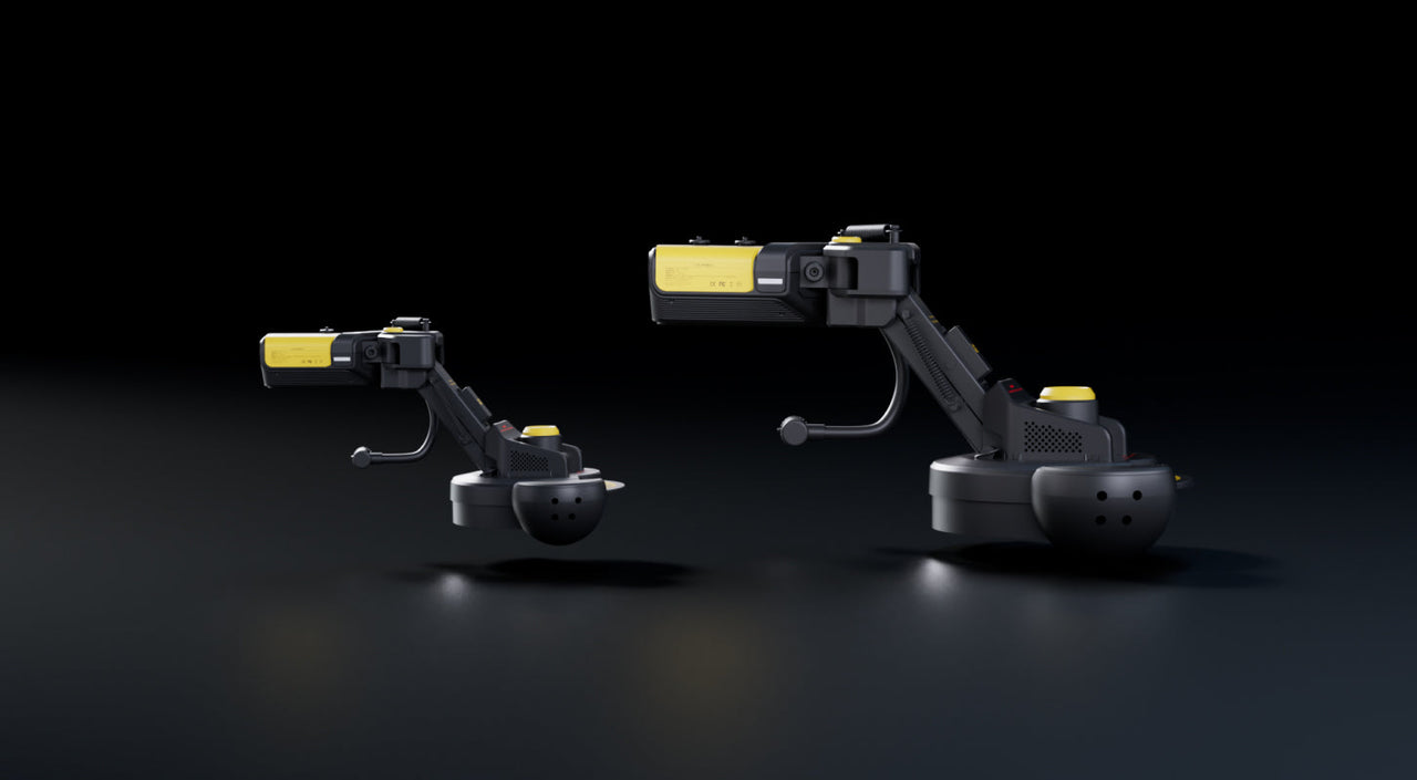 Two black and yellow robotic arms on circular bases, positioned side-by-side against a dark background with subtle lighting highlights.