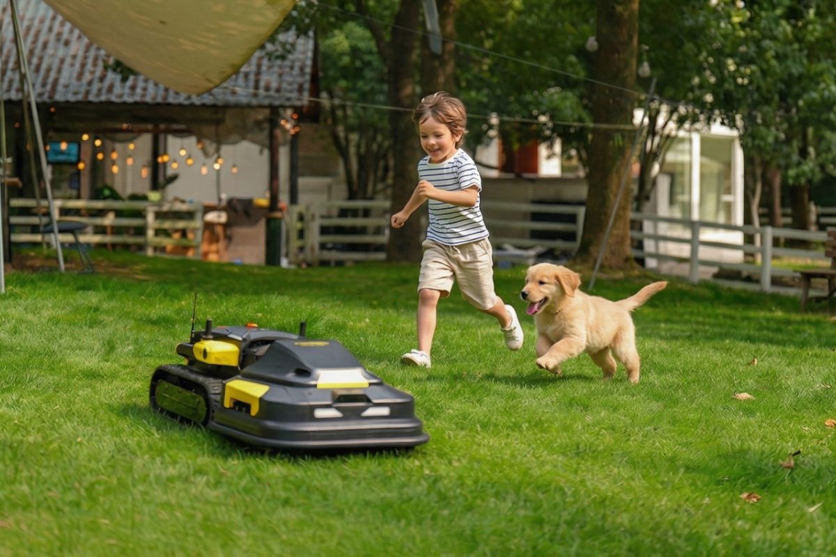 Child and golden puppy running on green lawn near black and yellow robotic lawn mower, backyard setting with trees and fence.
