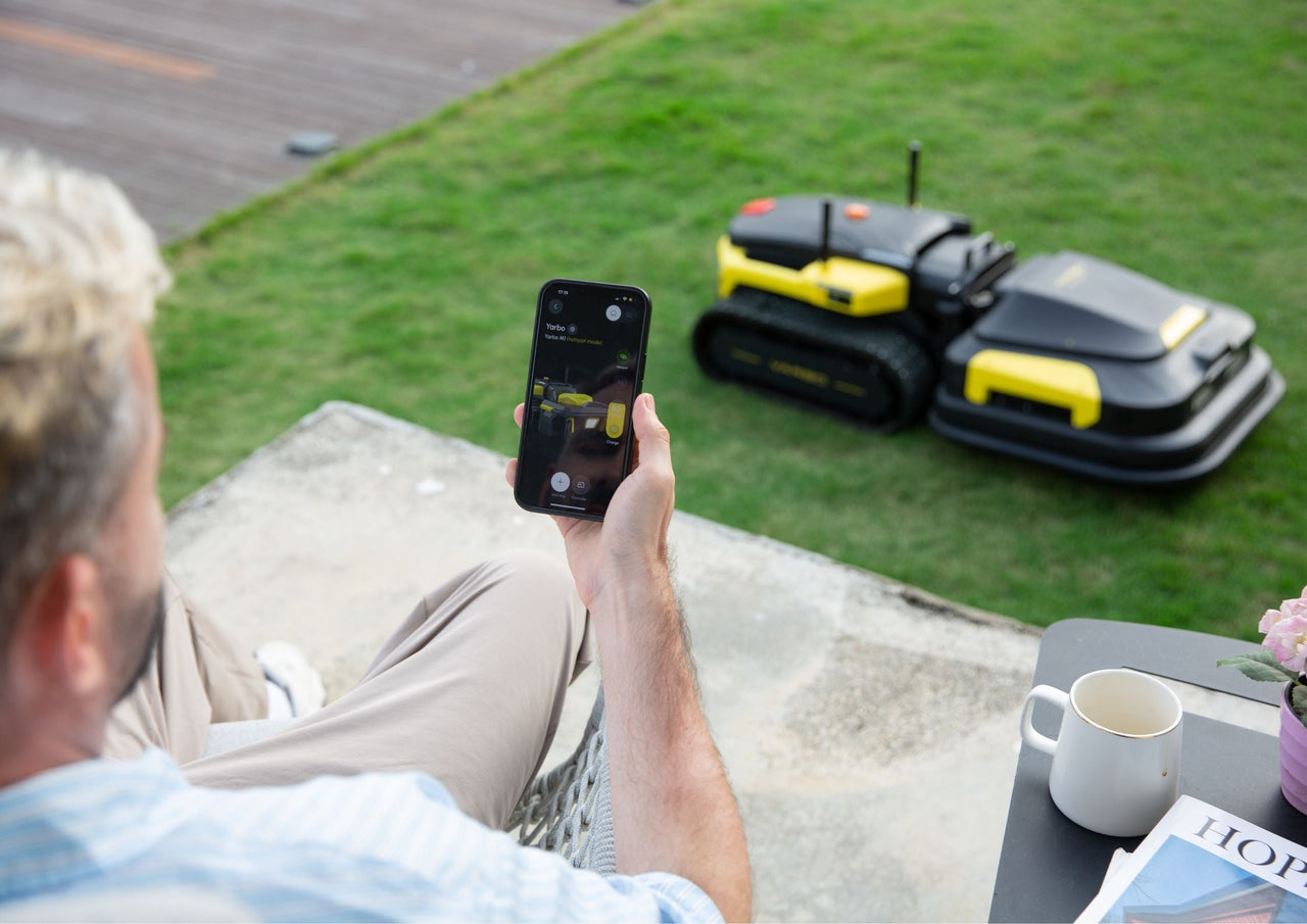 Man relaxes on patio, controlling Yarbo robot mowers via smartphone app, enjoying smart lawn care.