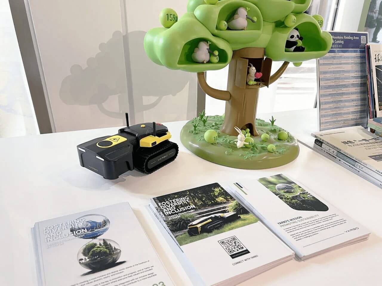 Yarbo robot mower beside eco-themed tree display and sustainability brochures at COP28 exhibit.
