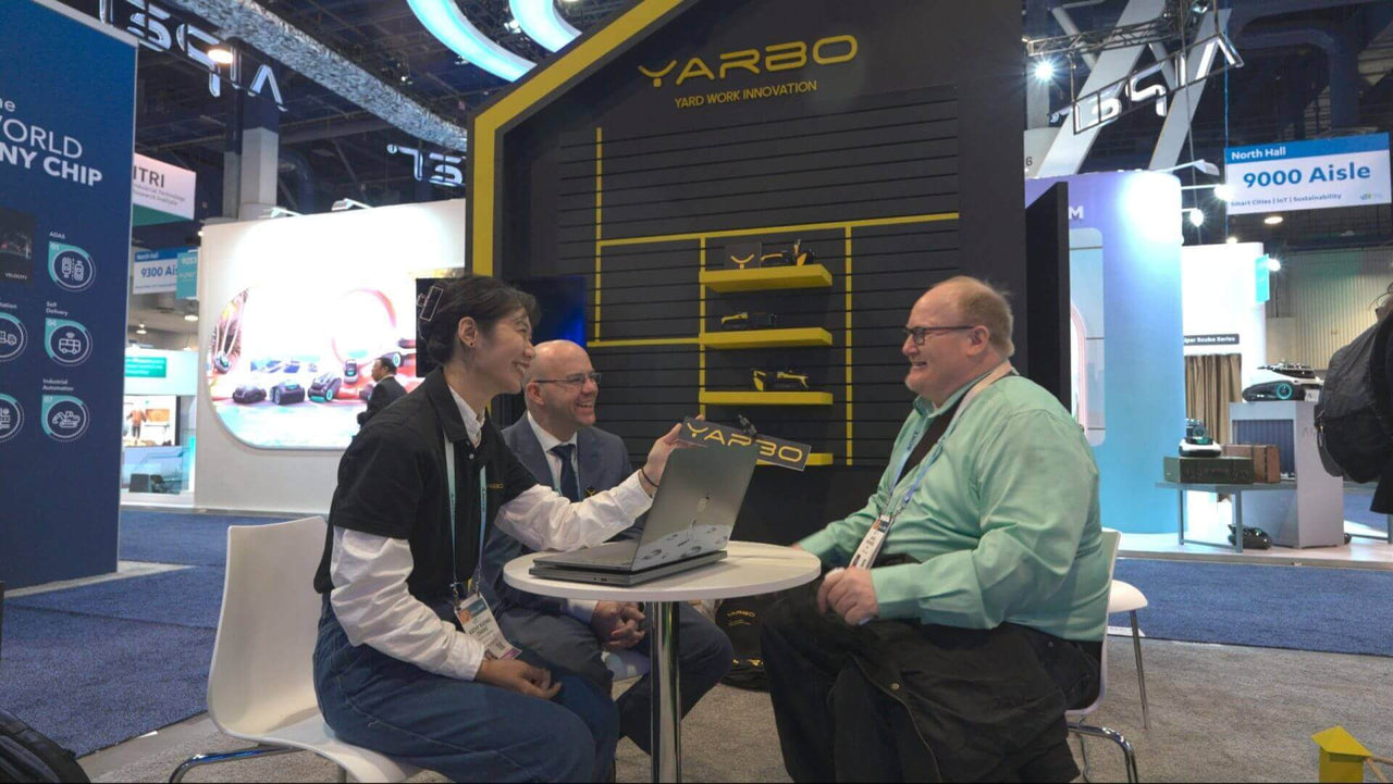James Richards laughs during a lively interview at YARBO’s trade show booth, surrounded by tech displays and engaged interviewers.