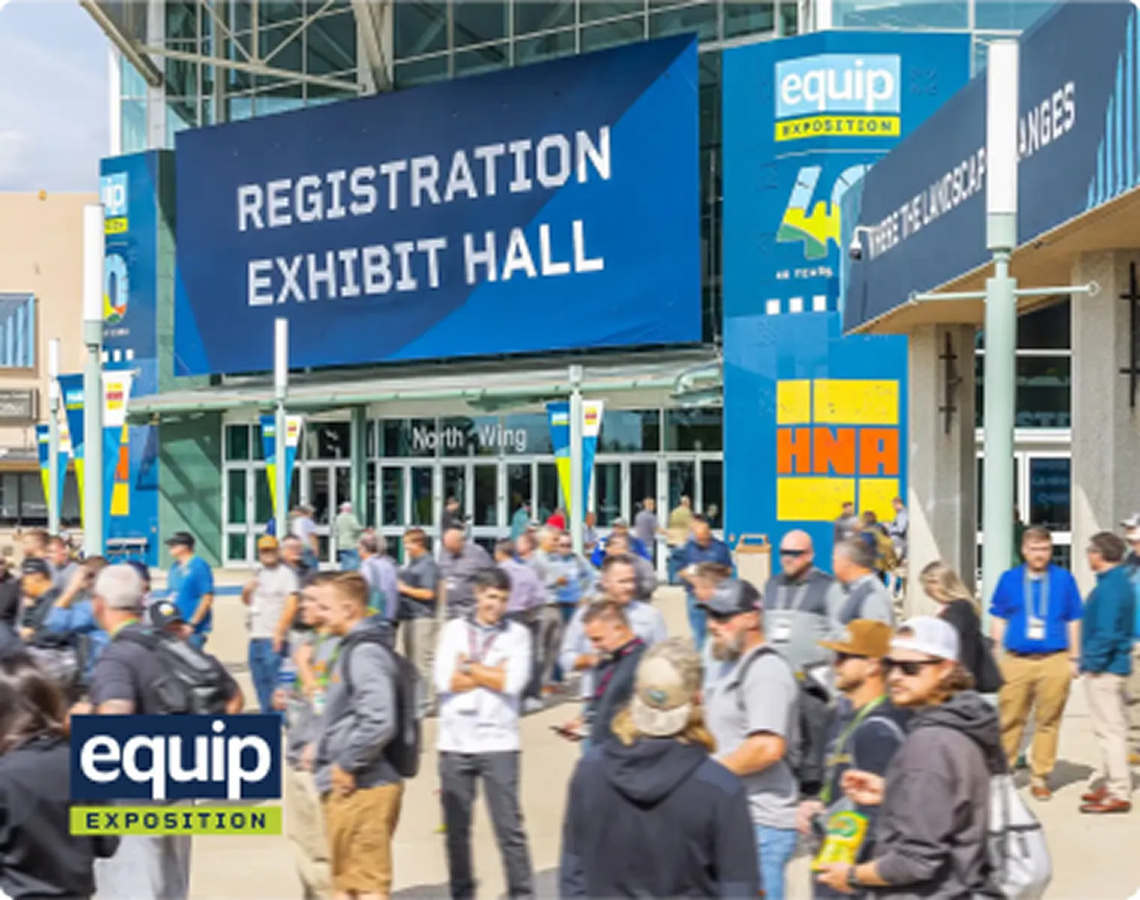 Crowd gathers outside Equip Exposition registration and exhibit hall under large blue banners on sunny day.