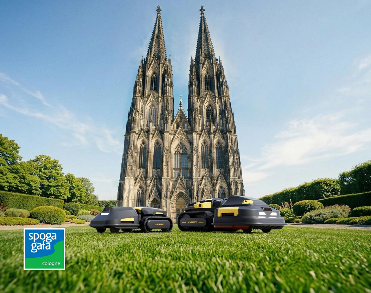 Three black and yellow YARBO robotic mowers on green lawn in front of Cologne Cathedral under blue sky; Spoga Gafa Cologne logo bottom left.