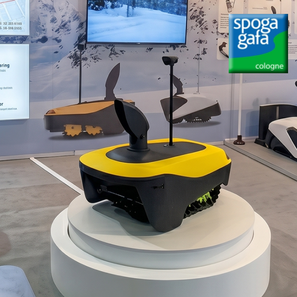 Yellow and black robotic lawn mower on white pedestal at Spoga Gafa Cologne trade show.