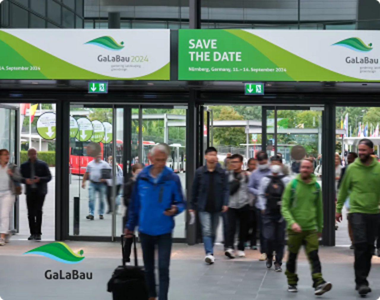 People entering GaLaBau 2024 exhibition in Nuremberg, Germany, under green and white banners with "Save the Date" text.