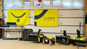 Yellow and black YARBO robotic mowers displayed in a showroom with branded banners on the wall.