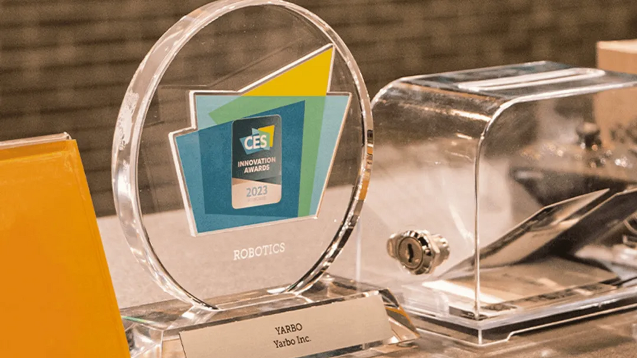 Clear circular CES Innovation Awards 2023 trophy for Robotics, engraved with YARBO, Yarbo Inc., beside a transparent toaster.