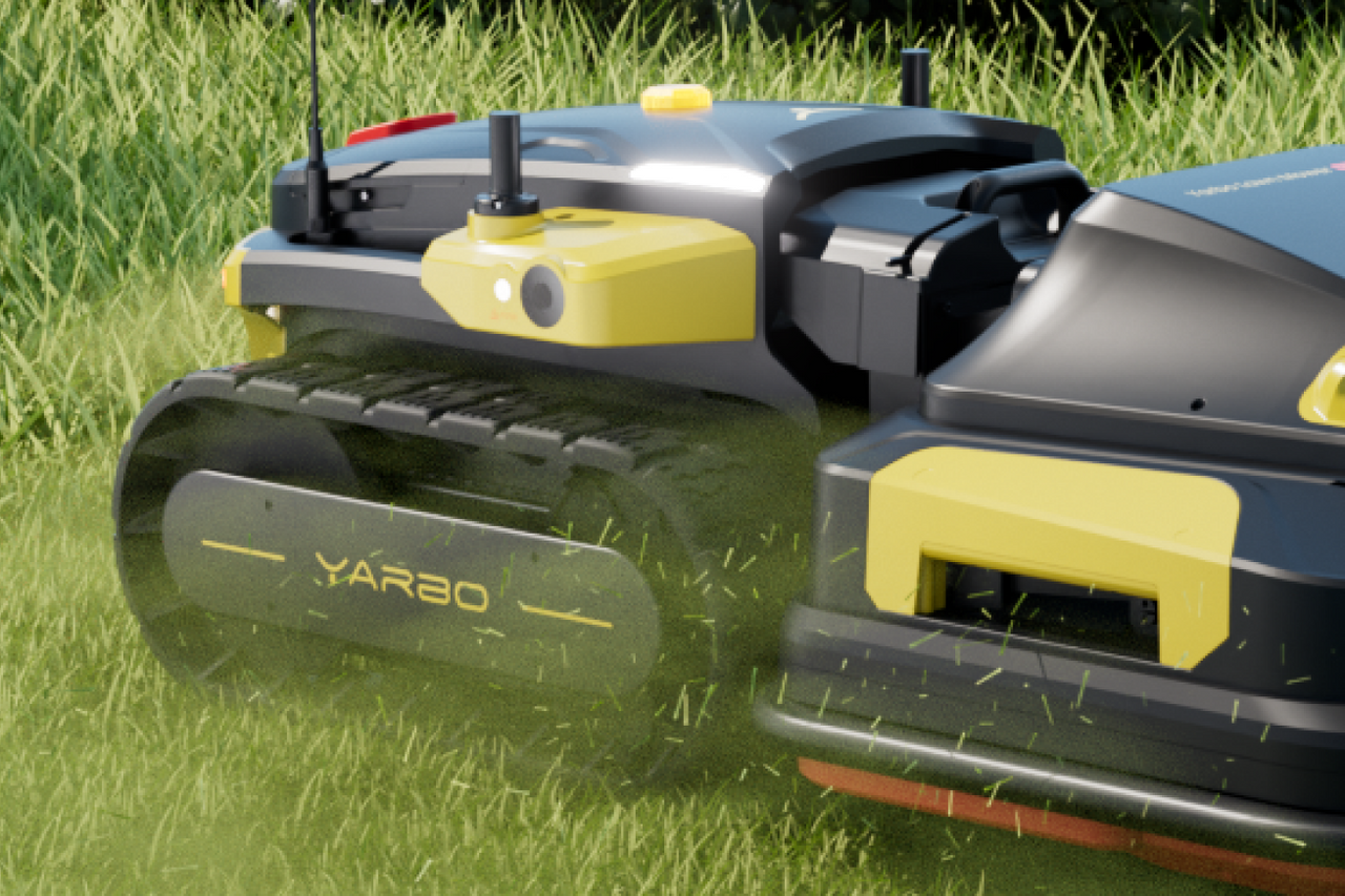 Black and yellow YARBO robotic lawn mower on green grass, cutting with visible clippings, side view.