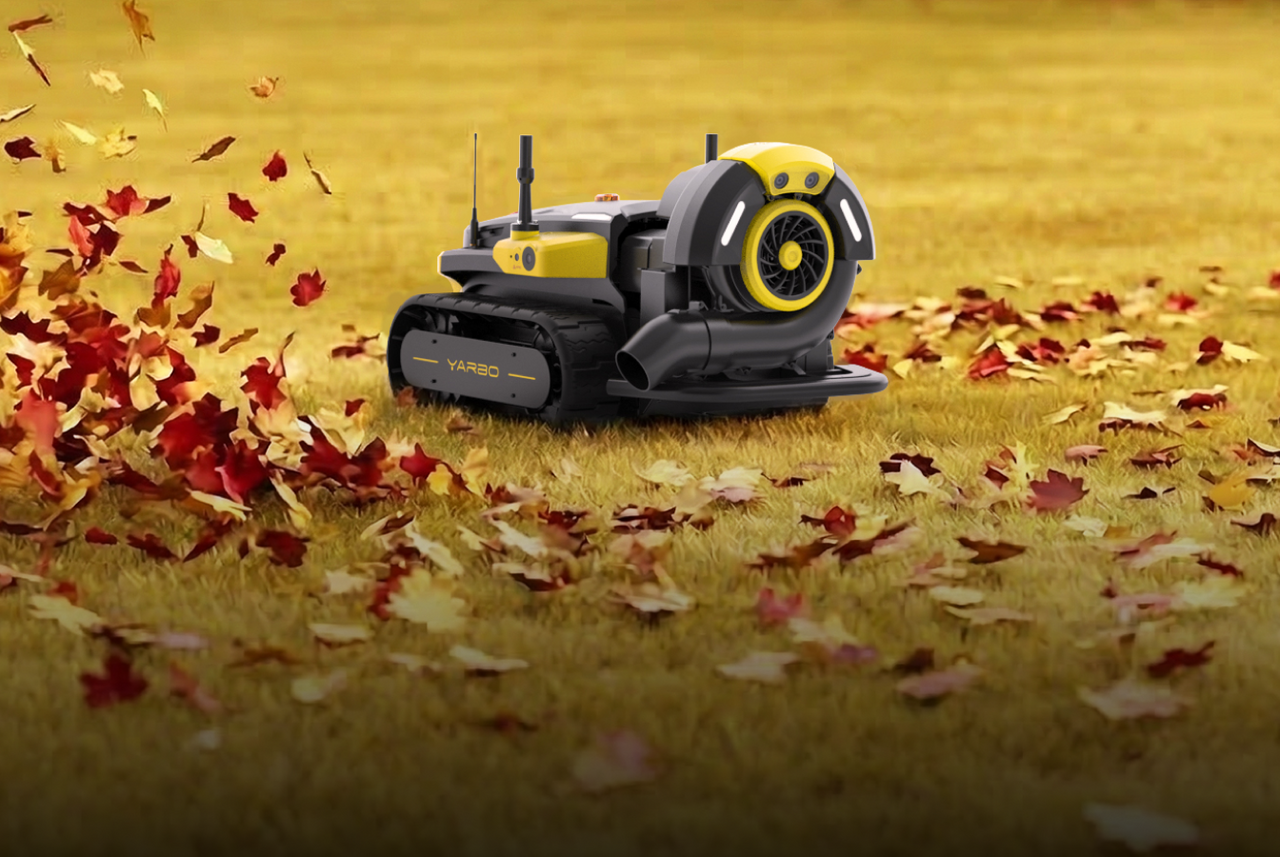 Yellow and black YARBO robotic leaf blower on grass, blowing red and orange autumn leaves.