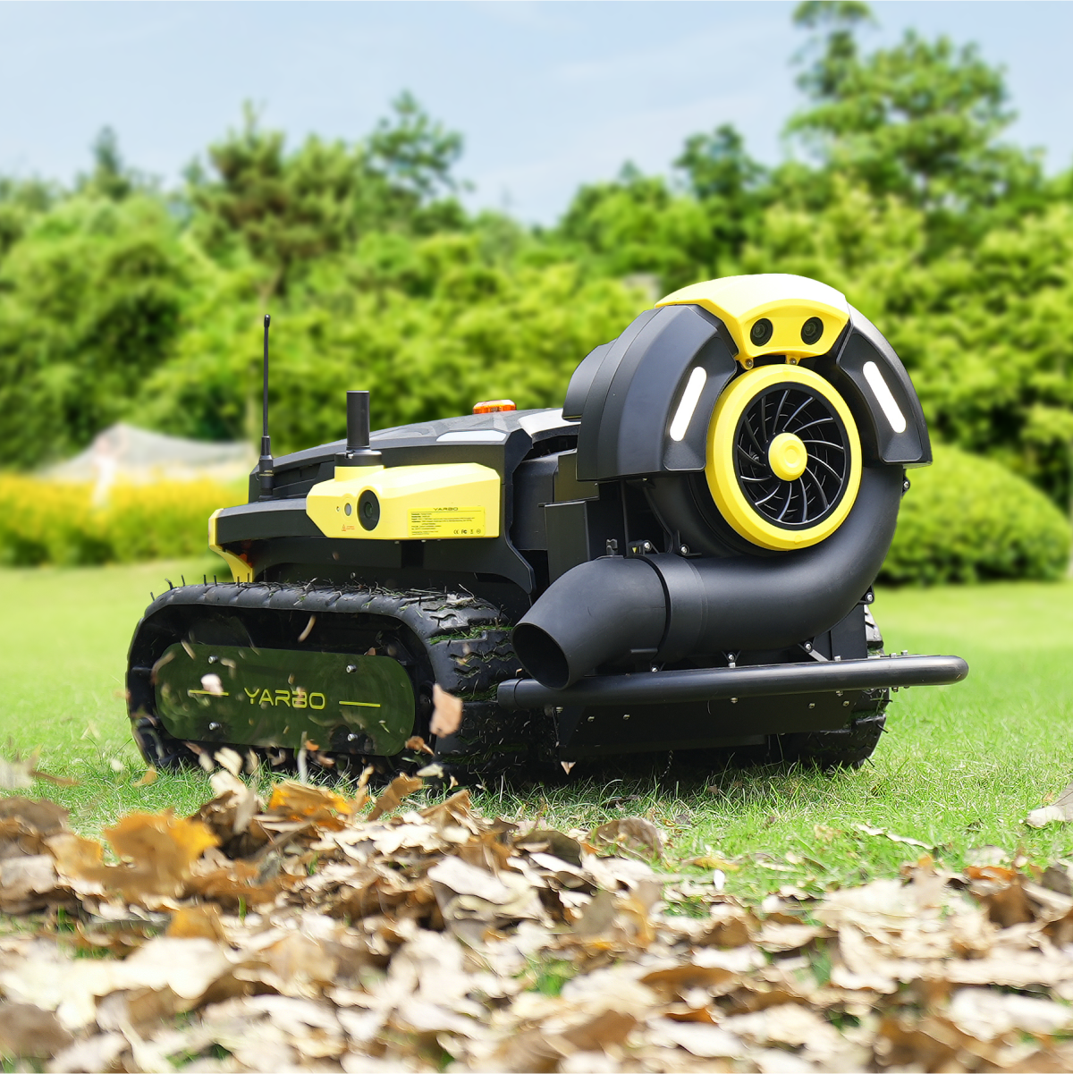 Black and yellow robotic lawn mower by Yarbo with tank treads, blower attachment, and debris collection in grassy yard.