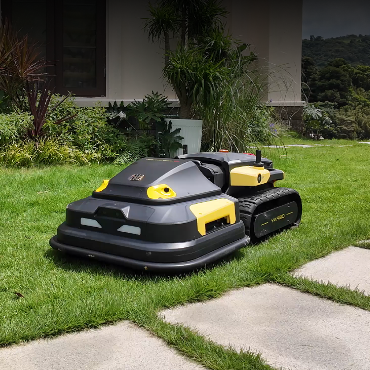 Black and yellow robotic lawn mower by Yarbo on grass, featuring tank treads and compact design, side view.