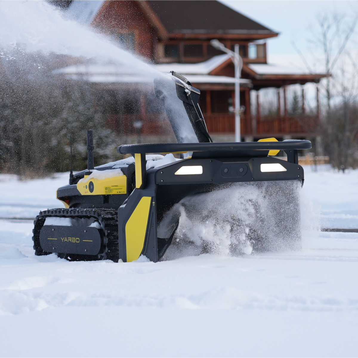 Black and yellow robotic snow blower by Yarbo clearing snow in winter yard, side view with tracks and illuminated panel